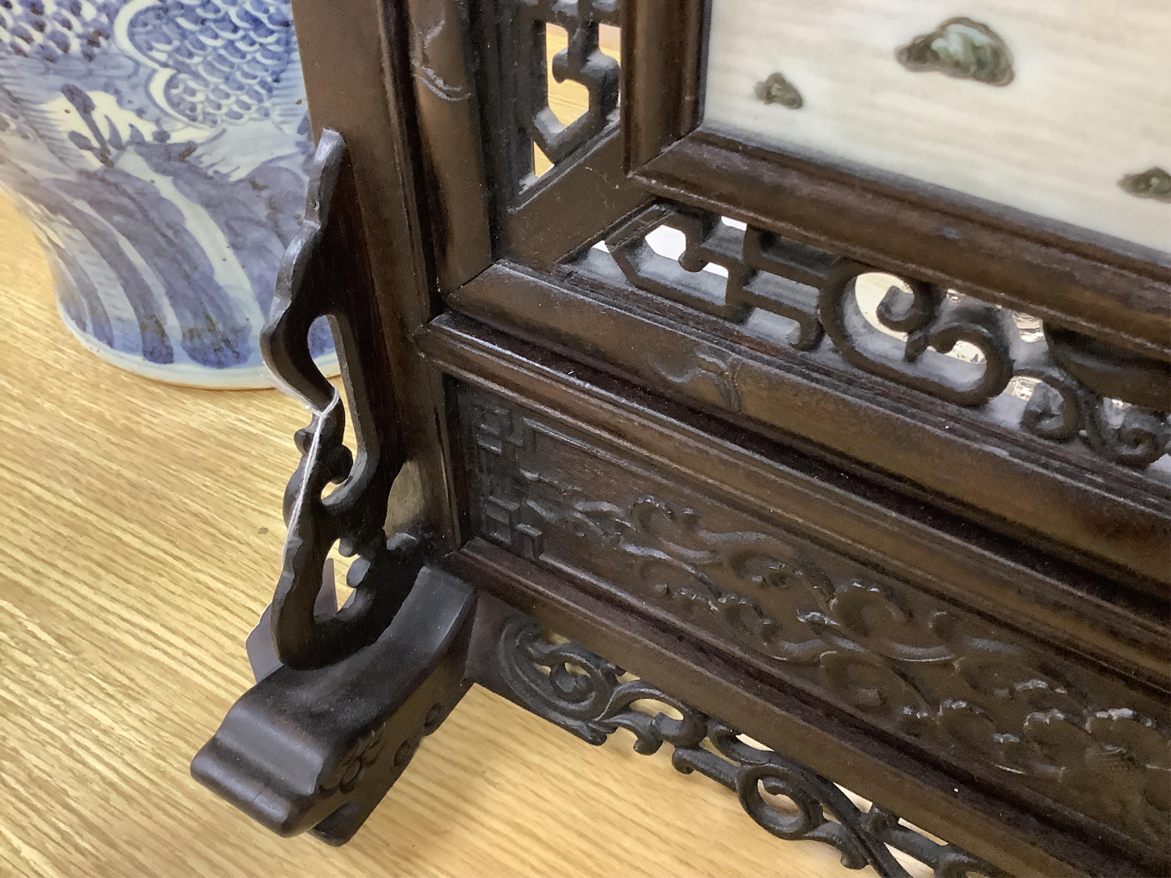 A Chinese carved wood table screen with a famille rose central plaque, screen 66cm high, plaque 35cm high. Condition - good